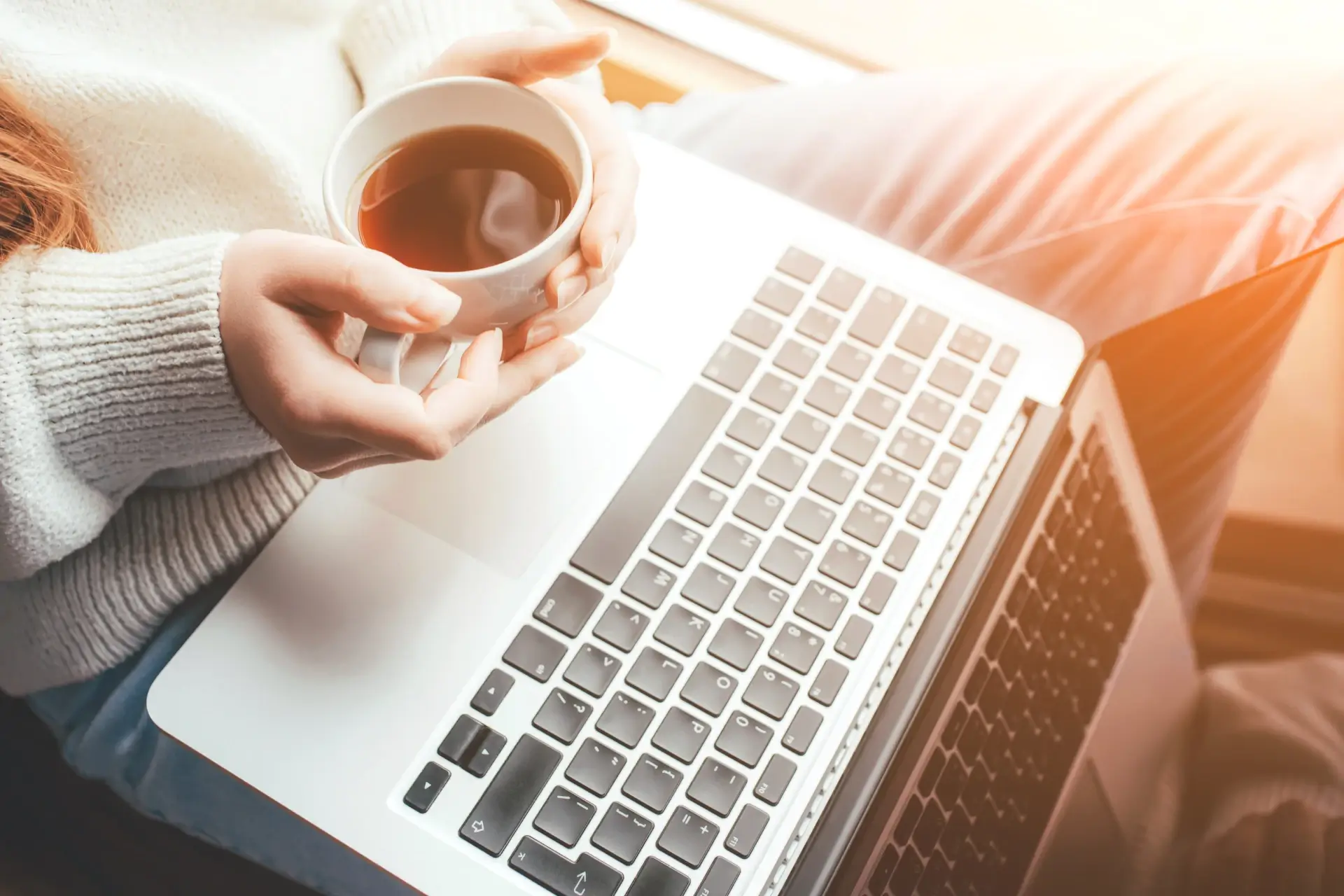 Frau am Laptop und Kaffee in der Hand und nimmt am virtuellen Sonntagscafe mit Gerlinde Reichardt teil